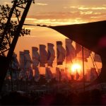 Sunset through The Glade stage and Other Stage flags